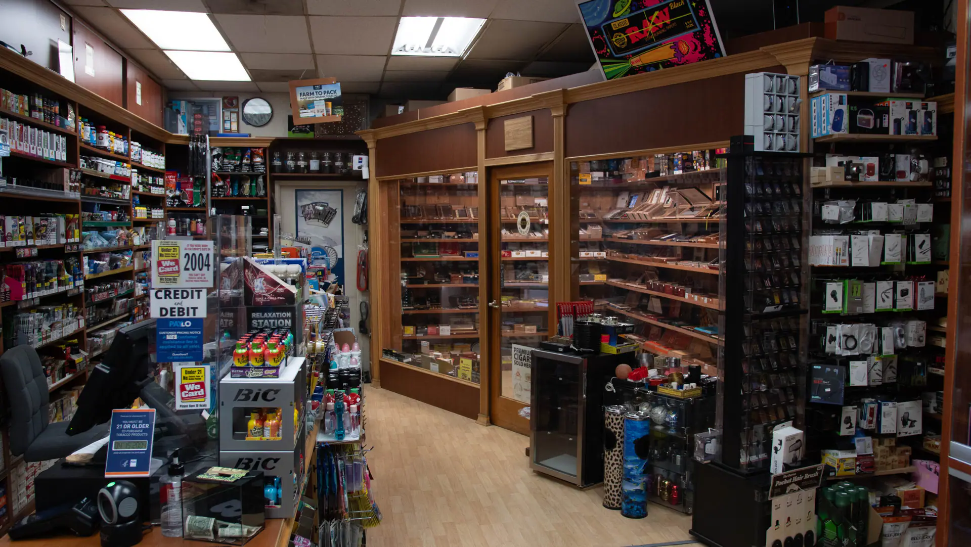 Inside La Brea Cigar & Cigarettes: the counter on the left and the glass-walled walk-in cigar humidor at the back